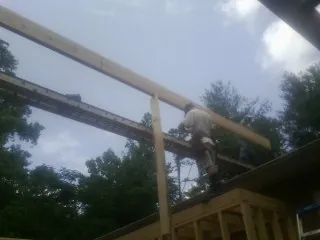 Carpenter setting a ridge beam over a new addition frame — Ice Dam Removal by Roofing Brothers in Petoskey