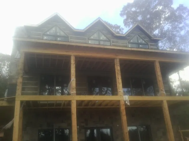 Dormers and porch framing on a large log home under construction — Roof Coating work by our crew in Petoskey