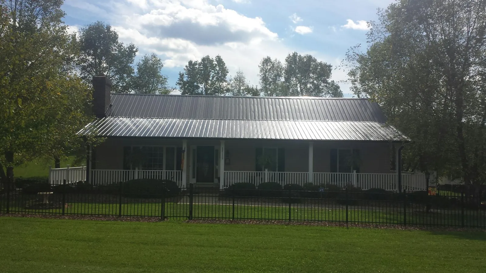 Gray metal roof on a brick ranch with a full width front porch — Gutter Guard Installation work by our crew in Petoskey