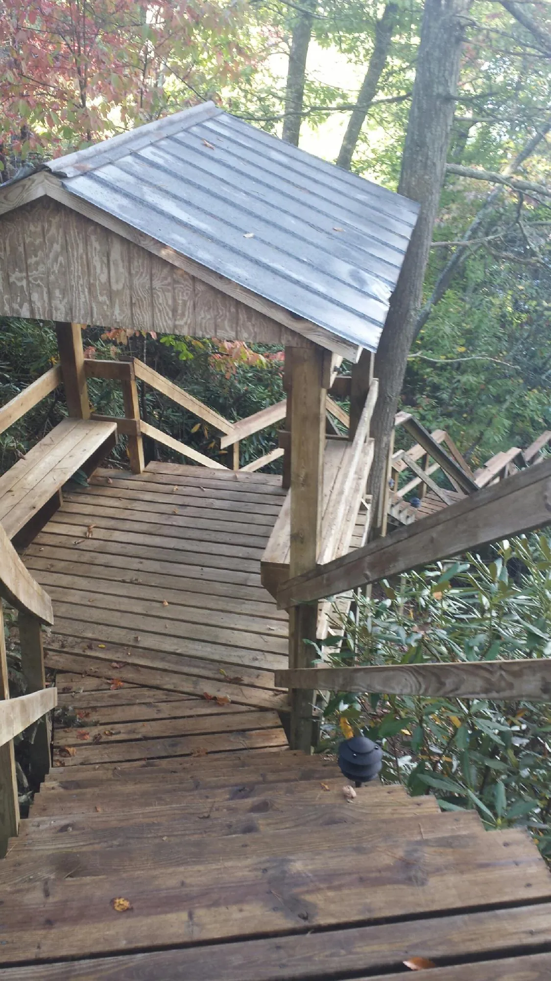 Metal roofed shelter over wooden steps on a wooded walkway — Skylight Repair & Installation work by our crew in Petoskey